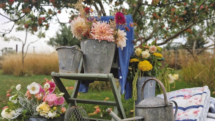 An autumnal display of flowers in grey metal buckets and a metal watering can.